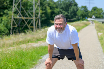 Exhausted healthy man taking a rest while out jogging