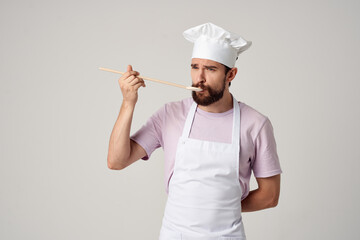 professional chef in uniform with a spoon in his hands work light background