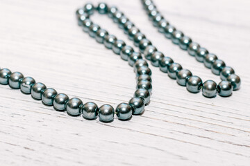 Gray large beads in a necklace on a wooden background.