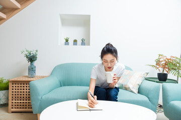 Young hipster woman writing journal on small notebook