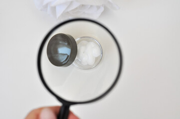 magnifying glass looking on hand cream in beauty bottle