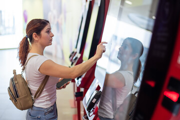 Caucasian woman buying cinema ticket at self-service box office.