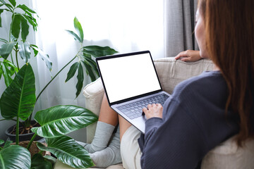 Mockup image of a woman using and working on laptop computer with blank white desktop screen at home