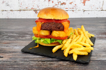 Cheeseburger with hash browns and French fries on a slate serving board