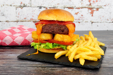 Cheeseburger with hash browns and French fries on a slate serving board