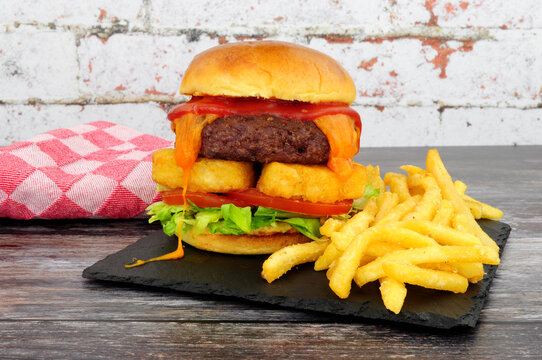 Cheeseburger with hash browns and French fries on a slate serving board
