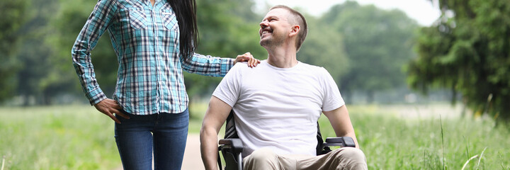 Smiling man in wheelchair walks in park with woman