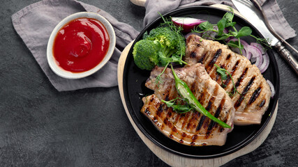 Sliced roasted pork meat on dark gray background. Organic gourmet food concept.