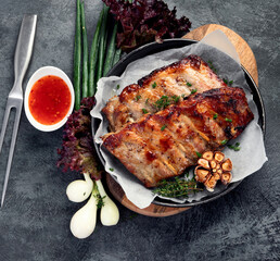 Roasted ribs with snacks and sauce on dark gray background. Gourmet cooking food concept.