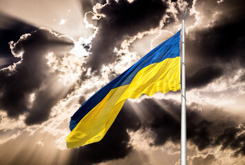 Blue and yellow national flag of Ukraine waving in the wind against the backdrop of the sunset sky