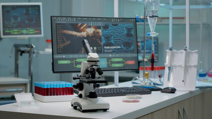 Microscope on laboratory desk with medical research equipment at hospital clinic. Modern technology used for scientific experiment with vacutainers, pipette and scientific computer