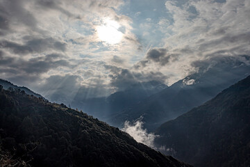 mountain valley covered with dense cloud and bleeding sun rays at morning from flat angle