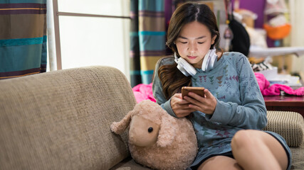 Asian woman play mobile phone on sofa