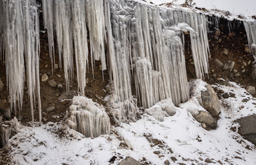 Fototapeta na wymiar frozen icicles sticking at mountain peak at winter in morning