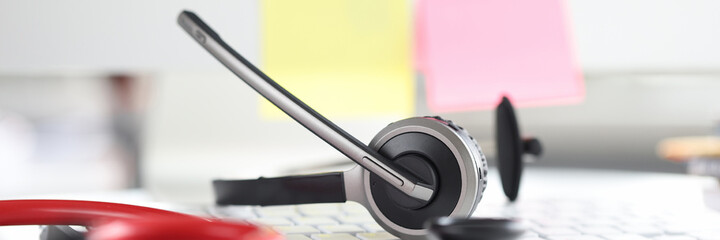 Stethoscope with headphones and microphone lie on computer keyboard