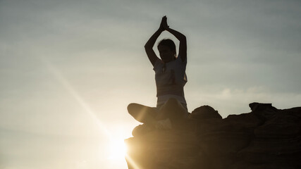 Silhouette Asian woman sit and perform lotus hands yoga meditation pose on mountain cliff peak during sunset. Bodybuilding and Sport exercise for healthy concept.