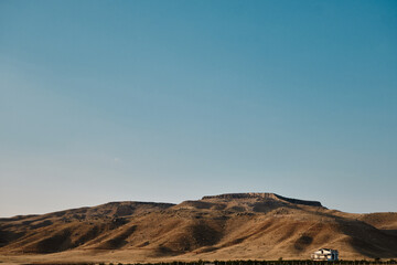 A single house behind the agricultural field and small hill with shadows on hills during sunset. Natural view of middle side of Turkey