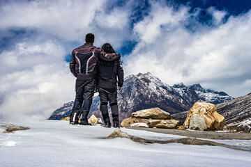 Naklejka na ściany i meble isolated young couple standing at mountain top and dramatic sky at day