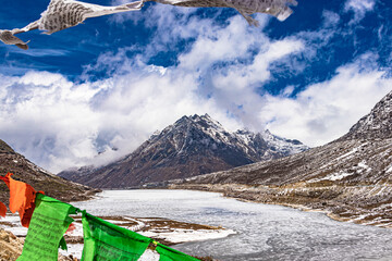 snow cap mountain with dramatic sky through the blurred buddhism flags frame at day