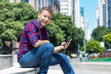 Handsome german young adult man sending message with mobile phone