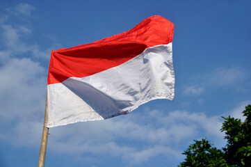 Fototapeta na wymiar Indonesia's red and white flag flying against blue sky background