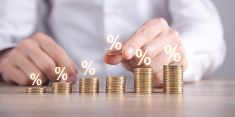 Man stacking coins with a percent symbols.