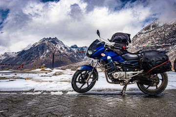 Obraz premium biker loaded bike at remote isolated road with snow cap mountains at background