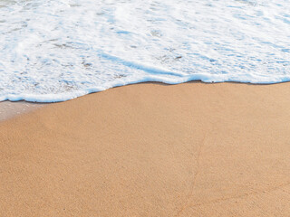 Fototapeta na wymiar horizontal shot: sea foam wave on a sandy beach, copy space