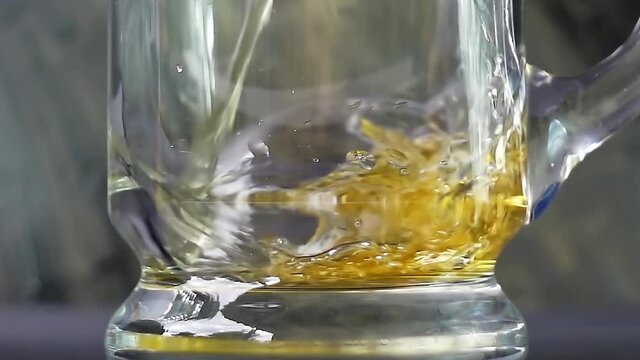 Beer is pouring into a beer mug with bubbles on a black background. 4k slow motion video with the camera moving down.