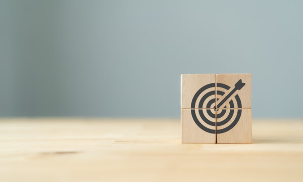 Business goal and success concept.  Focus on a goal and achieve successful business. Initiation for planning to reach target. Darts target aim icon on wooden cubes with grey background. Copy space. 
