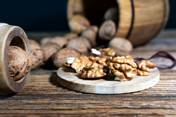 walnuts sprinkled from a wooden barrel onto an old board, peeled nuts on a wooden board.