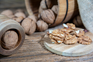 walnuts sprinkled from a wooden barrel onto an old board, peeled nuts on a wooden board.