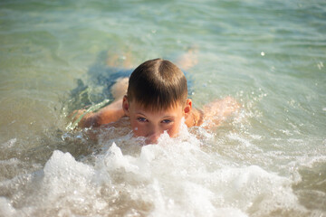 Fototapeta na wymiar The boy swims in the sea. Face in sea foam. Satisfied emotions. Pleasure