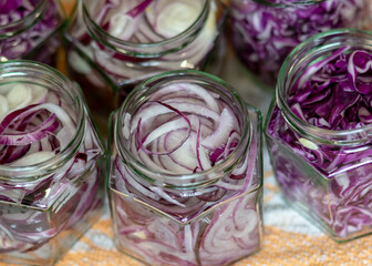 Fototapeta premium glass jars with sliced red cabbage and onions, vegetables prepared for home canning, autumn harvest time