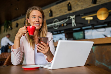Close up of hands using mobile application on smartphone, woman checking emails on her smart phone in cafe. Surfing the net in the coffee break. 