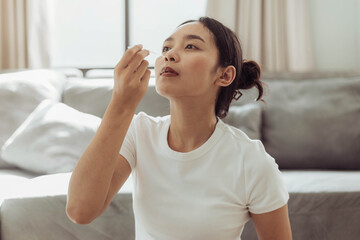 Young woman self test for COVID-19 at home with a nasal swab. asian woman using coronavirus covid-19 rapid antigen home testing kit, Coronavirus nasal swab test for infection. - obrazy, fototapety, plakaty