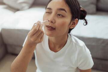 Young woman self test for COVID-19 at home with a nasal swab. asian woman using coronavirus covid-19 rapid antigen home testing kit, Coronavirus nasal swab test for infection.