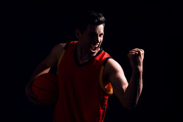 Basketball player with ball on black background