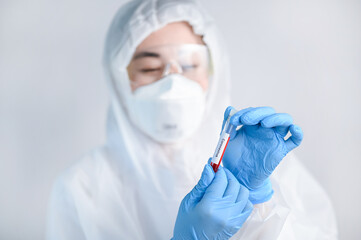 Selective focus of Corona virus blood sample in doctor hand in PPE suit.