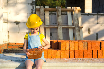 Little girl in a yellow hardhat is playing builder on the construction site of her future home....