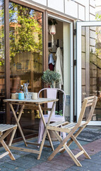 Outdoor cafe terrace with wooden table and chairs by the window with an entrance door. Street cafe.