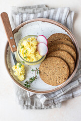 Plate with tartlets, multigrain crackers with egg pate or salad served with radish and thyme.