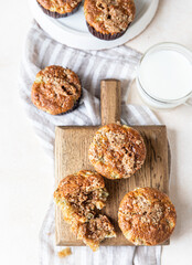 Freshly baked muffins with oat crumbs on wooden board with a cup of milk for healthy breakfast or snack.