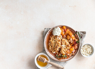 Ceramic plate with tasty plum crumble dessert served with vanilla ice cream and herbs. Top view. Copy space.