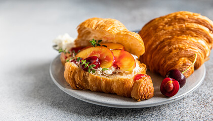 Croissant with nectarine, cherry and ricotta cheese, gray stone background. Tasty breakfast. Close up.