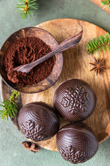 Tasty cocoa bombs with marshmallow and chocolate on wooden plate with fir branches and spices. Trendy winter hot drink. Top view.