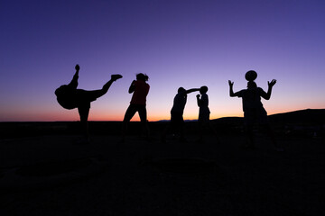 silhouette of five children at sunset playing different sports
