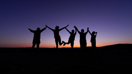 silhouette of a group of children jumping in the sunset