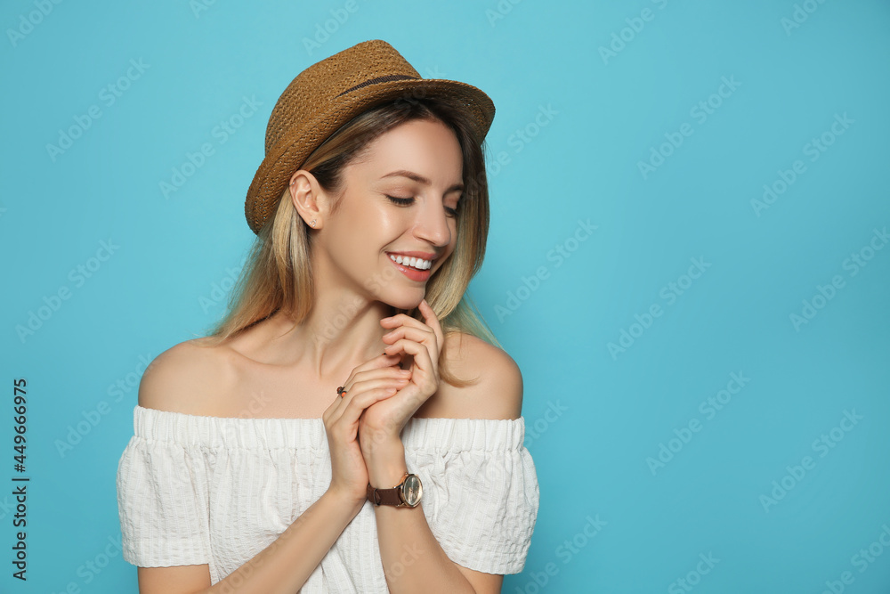 Wall mural Beautiful young woman wearing straw hat on light blue background, space for text. Stylish headdress