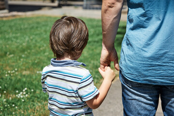 Dad takes a little boy, son by the hand to kindergarten or school on a sunny day. Care of parents,...